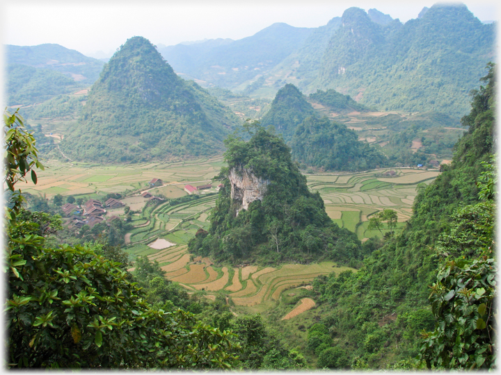 Lone karst with fields and village around it.