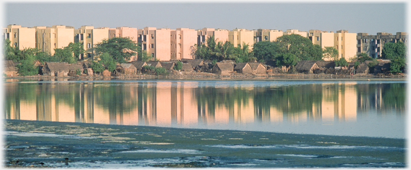 New flats by old huts at the water's edge.