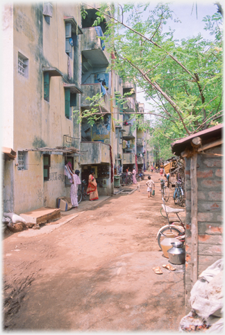 Block of flats by lane, children playing in distance.
