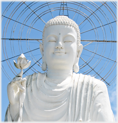 Head and shoulders of Van Hanh Buddha with circular lights behind.