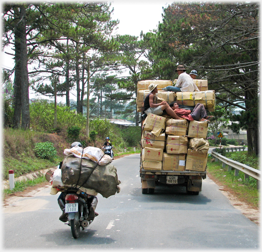 High loaded truck with men on top of it.