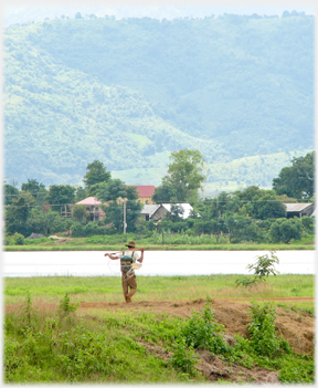 Fisherman walking by lake.