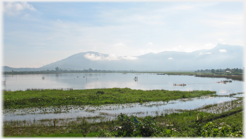 Morning view over laake to hills, with fishing nets and fisherman.