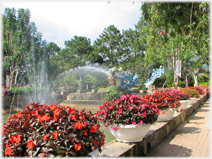 Line of pots of imatiens beside pool and fountains.