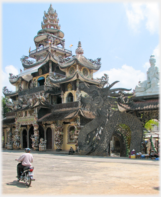 A broader view of the main entrance with the street and a motorcyclist.