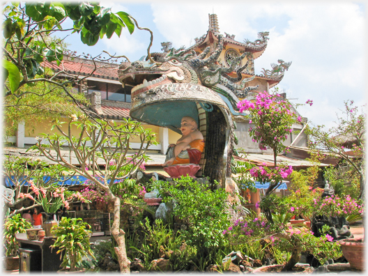 Head of the dragon over a plump Buddha figure.