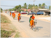 Monks ridding bicycles holding umbrellas.