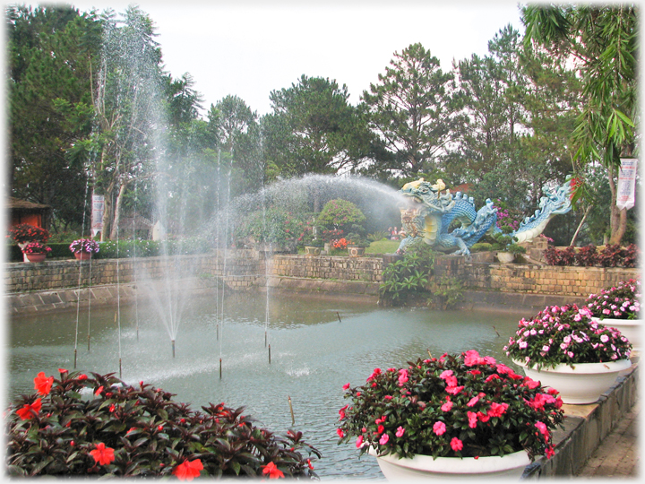 Display pond with surrounding tubs of flowers and floutains.