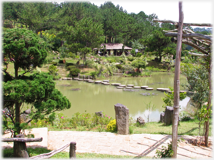 Stepping stones across lake with pavilion on far bank.