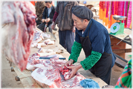 Butcher with green sleves and his meat.