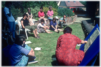 Group of people in garden watching someone teach.