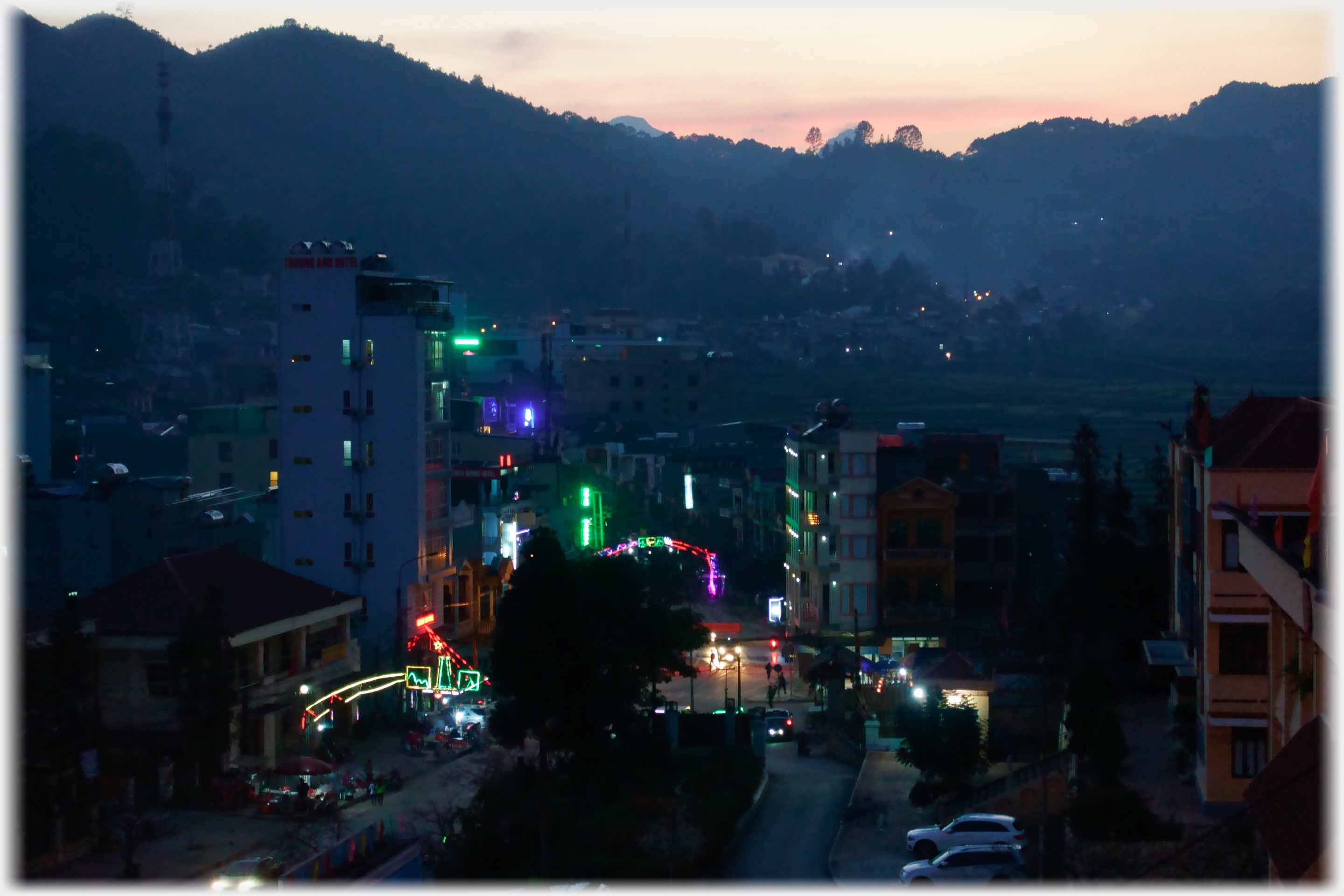 End of sun setting, neon lights on buildings of street.