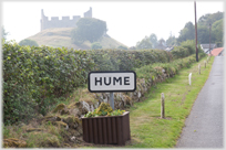Village sign 'Hume' with castelations in the background.