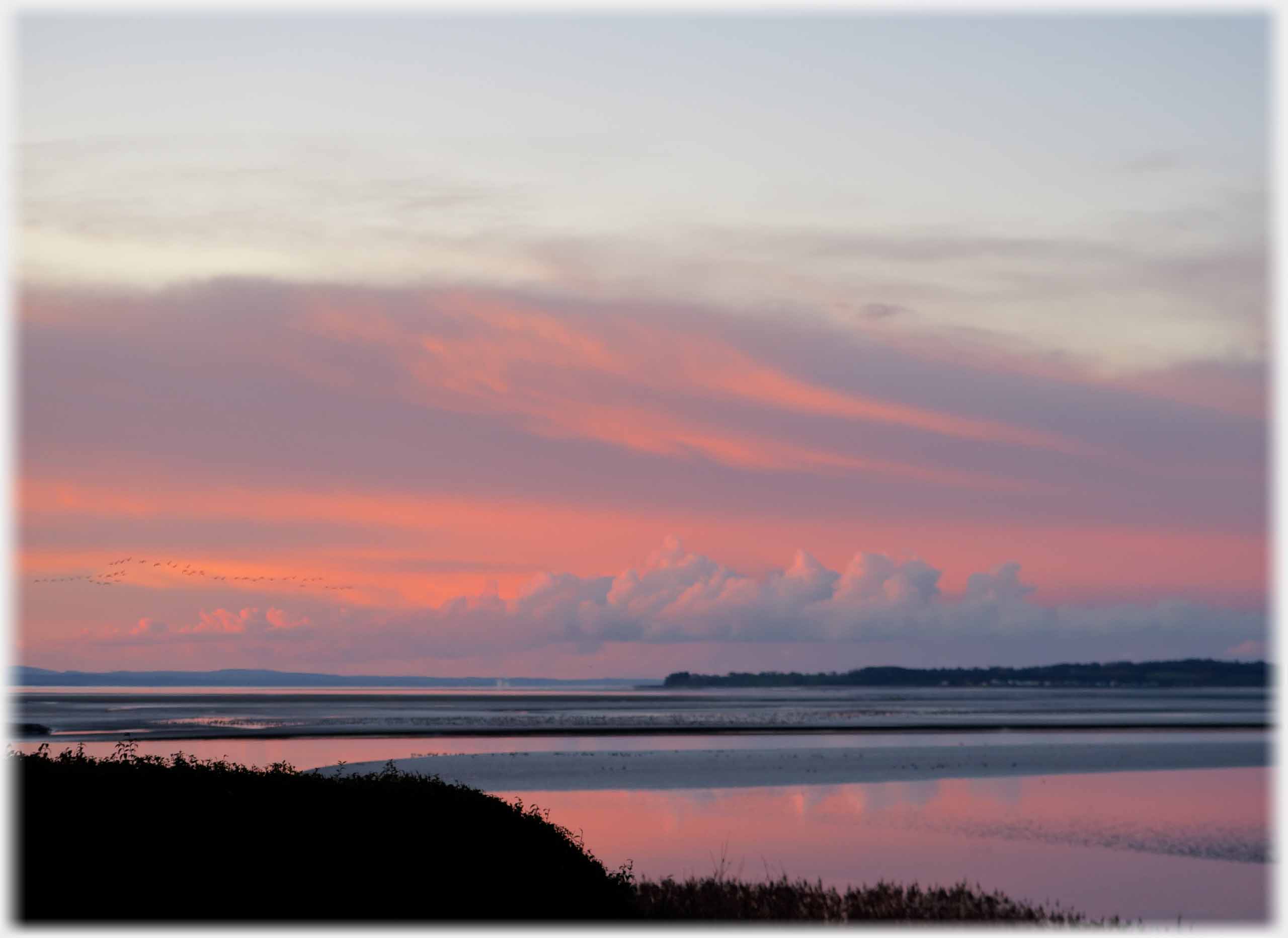 Bank of clouds against pink sky and its part reflection.
