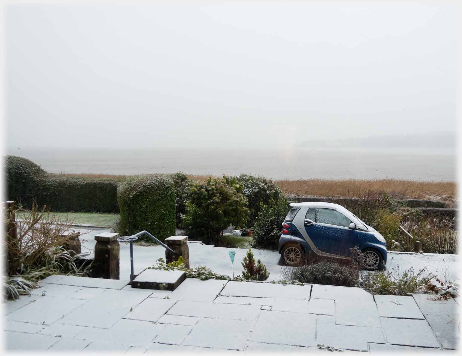 Car and patio with a covering of light snow.