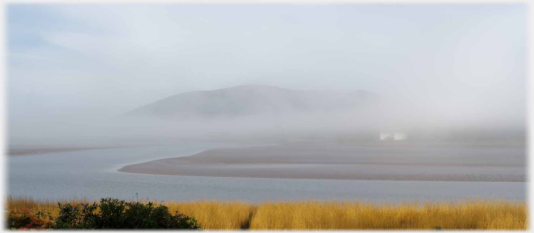 Hill and water seen through mist.