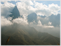 Clouds in and out of high conical mountains.