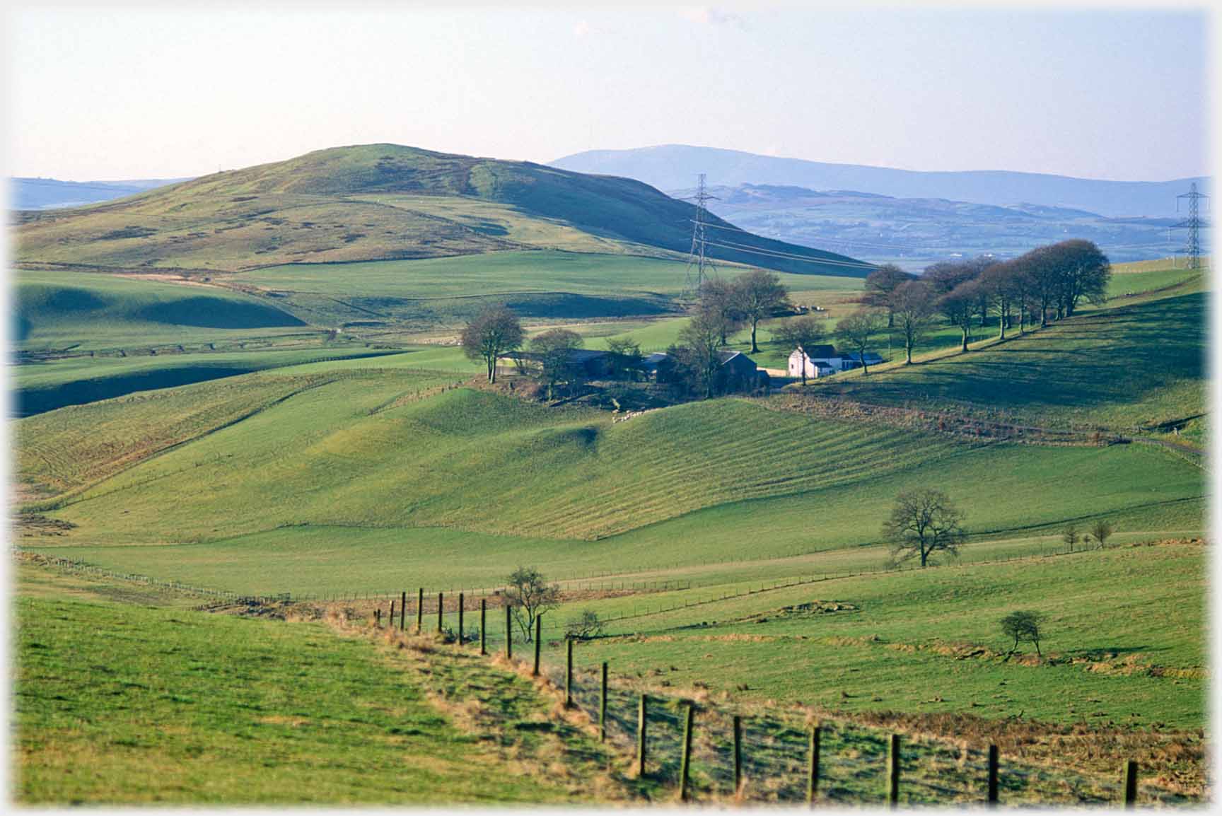 Small hill with house amongst trees beside it.