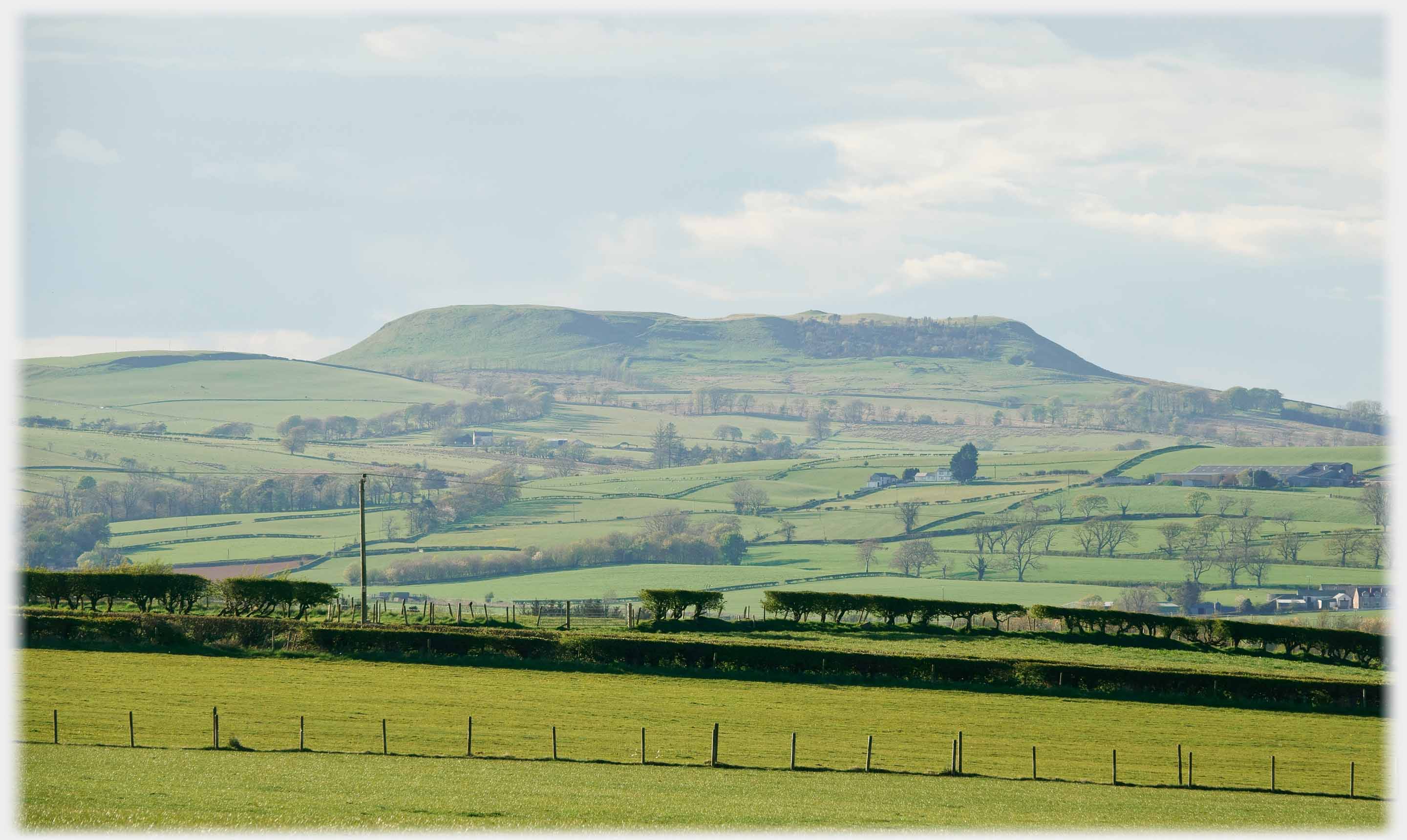 Flat topped hill with laandscape of fields in foreground.