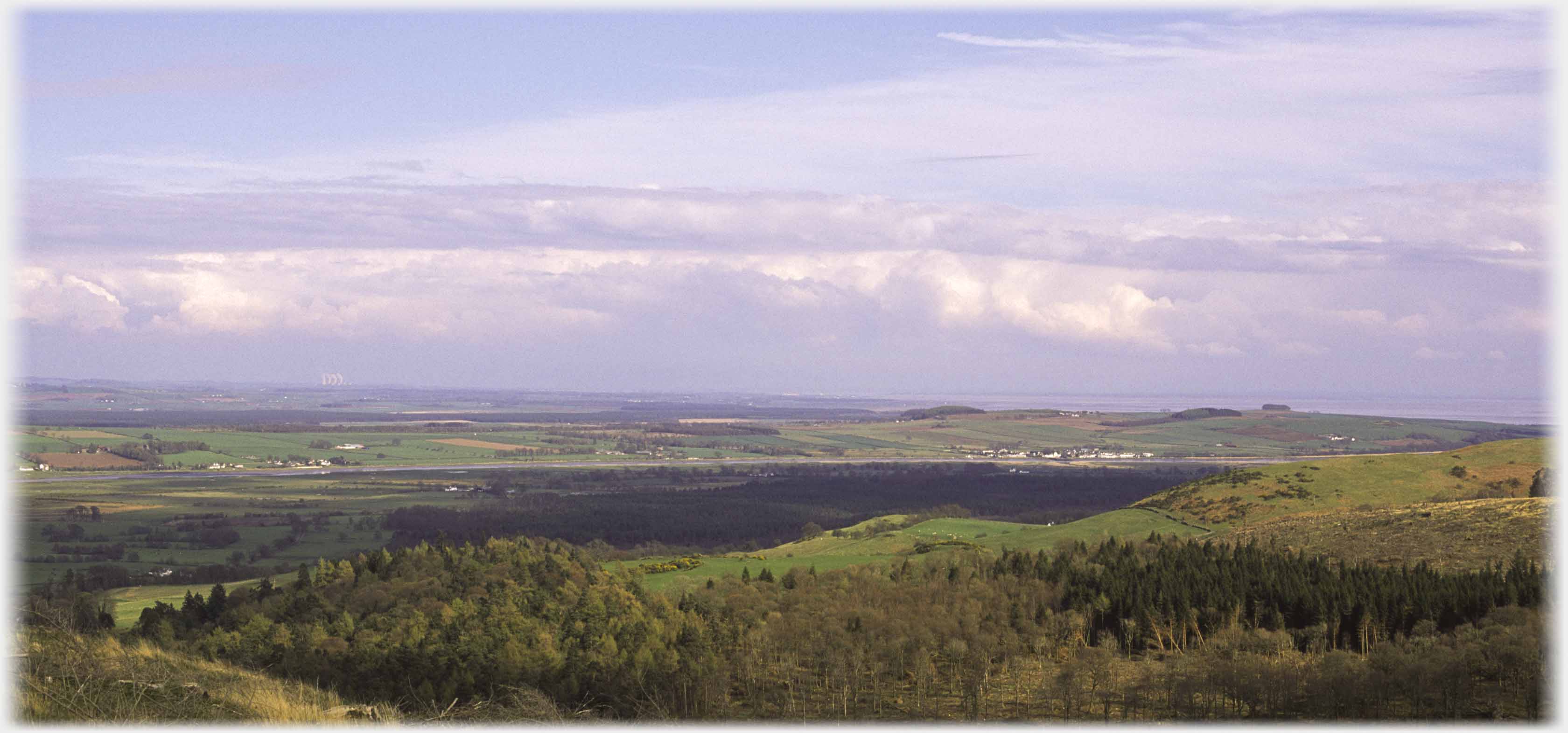 Distant landscape with trees in foreground, white houses of communities in distance.
