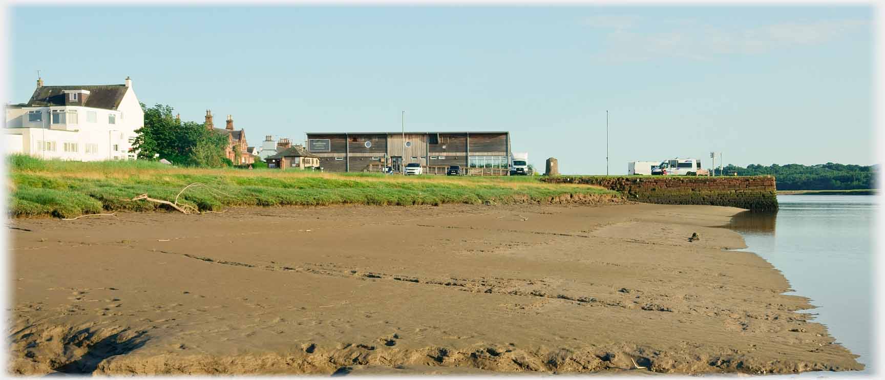 Muddy river bank, buildings and pier.