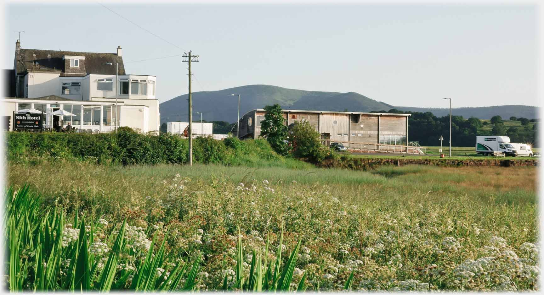 Three story building and wooden building hill beyond.