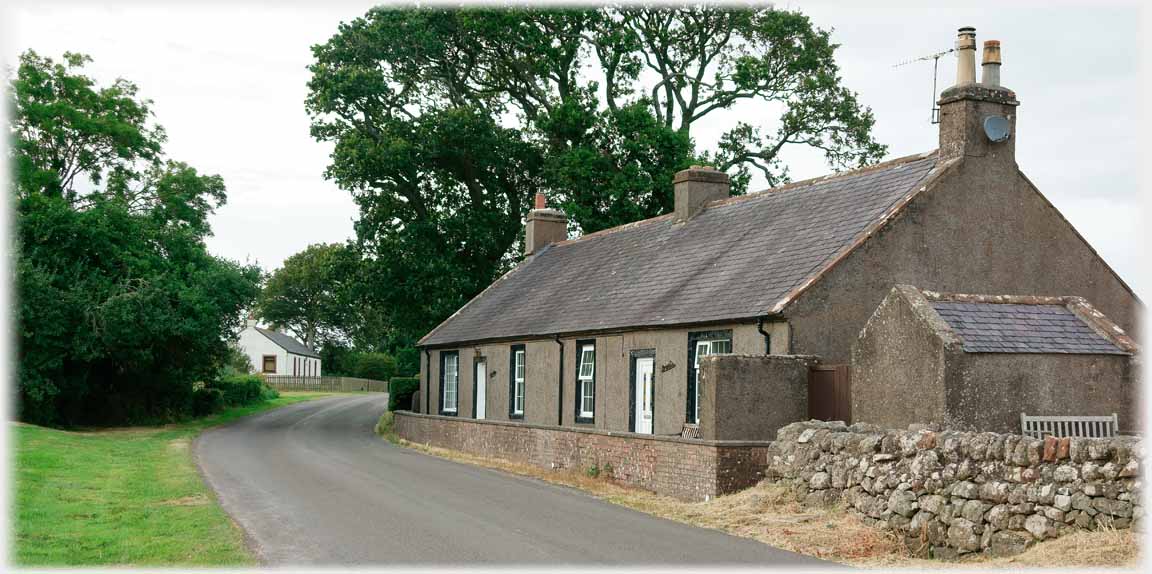 Pair of single story cottages by road.