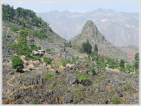 Craggy rock strewn landscape with indistinct houses.