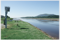 Brazier on pole by river.