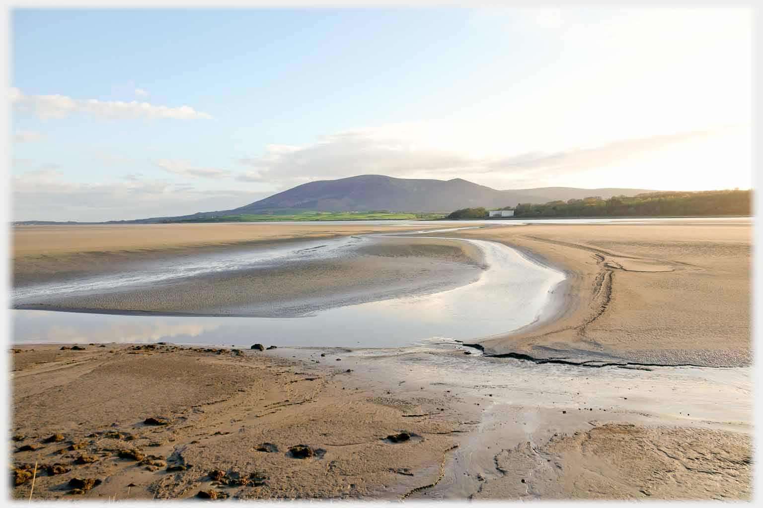 Sands at low tide with hill on horizon.