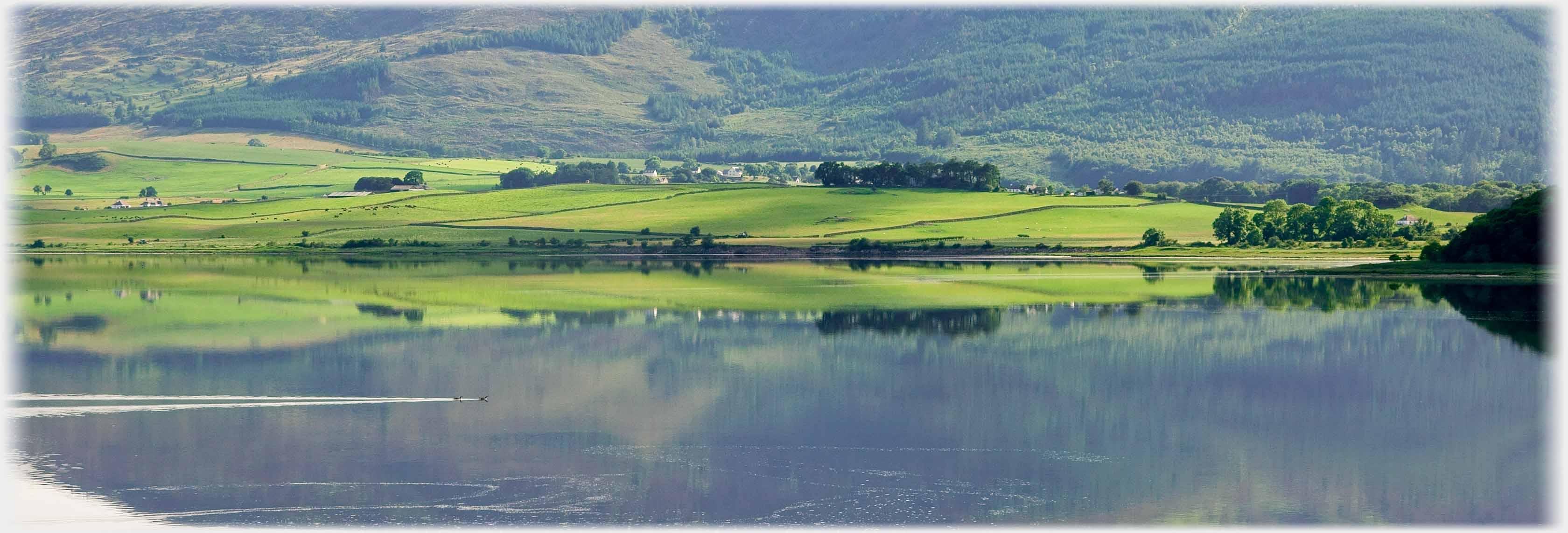 Long strip of country reflected in still water.