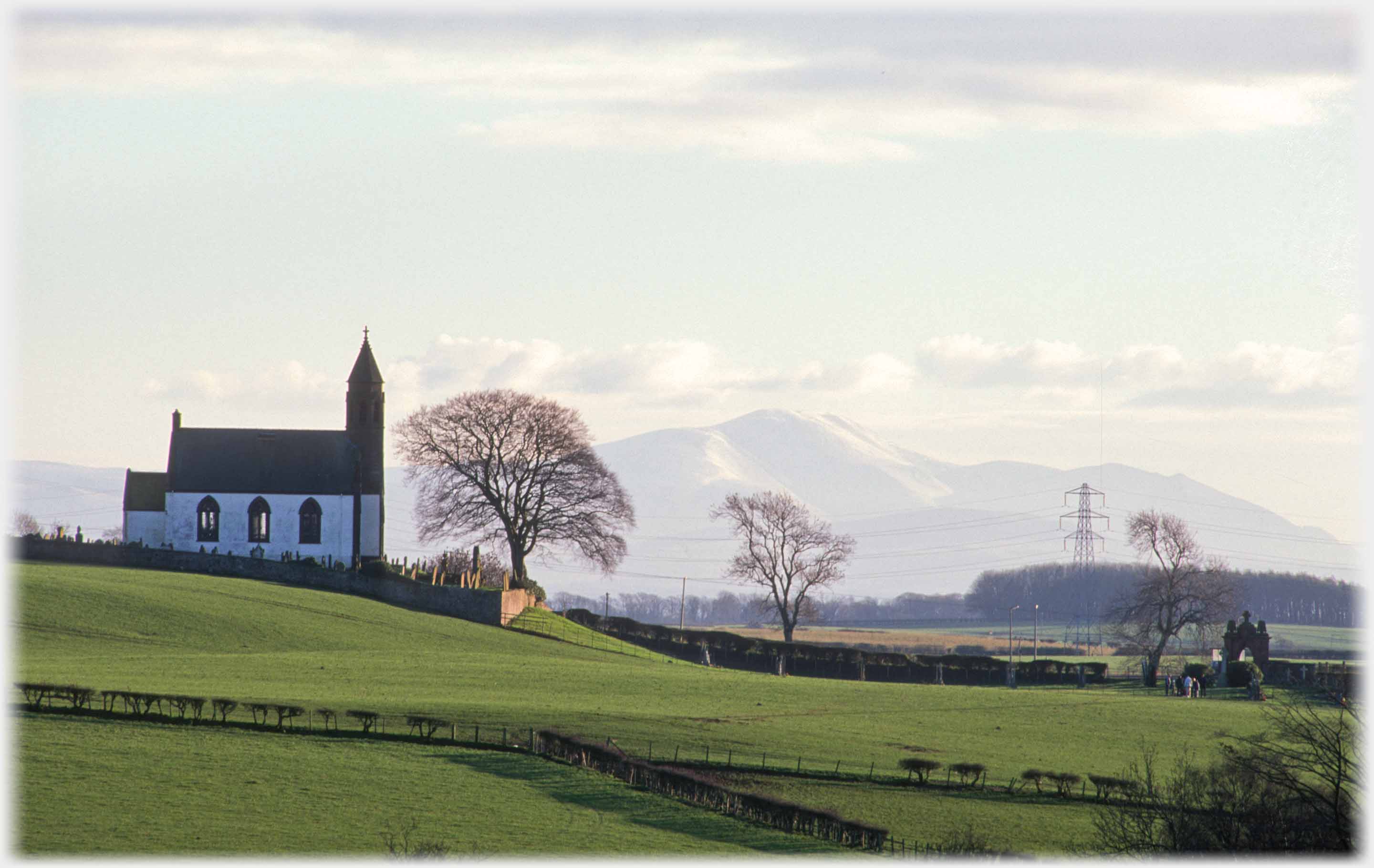 Church raised on slight hill with distant mountain.