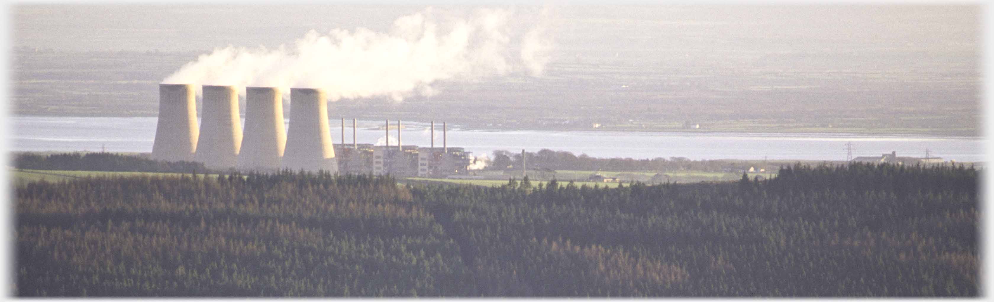 Four steaming cooling chimneys and three visible reactors.