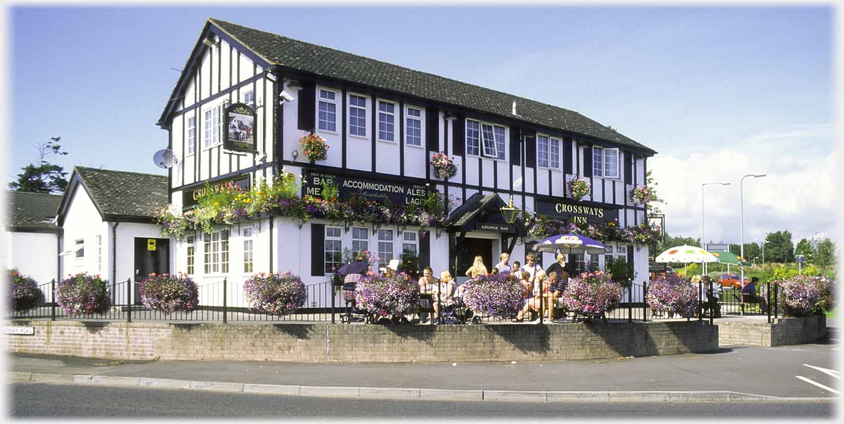 Black and white two story building, forecourt with people.
