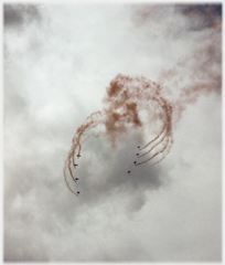 Team of sky divers with flares forming pattern.