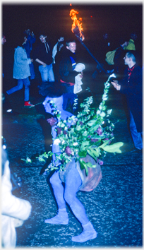 Blue figure holding bunch of foliage.