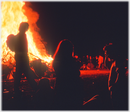 Outline of figures against enlarging bonfire.