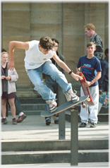 Skate boarder on board in the air, being watched.