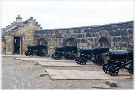 Four cannons with barrels through wall.