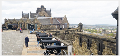 Line of cannons with building beyond.