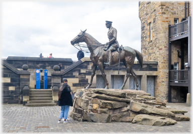 Person standing beside horseman.