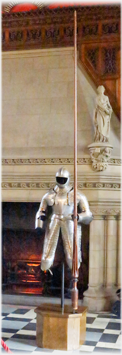 A full suit of armour with avery long lance on a pedestal.