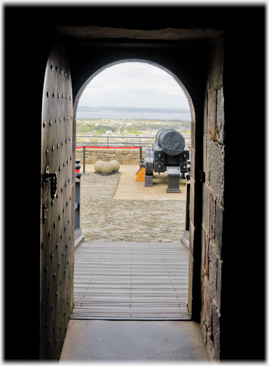 Looking out of door to distance, large cannon in foreground.