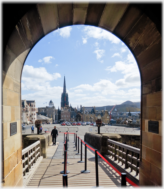 Looking through curved stone arch at esplanade and church spire.