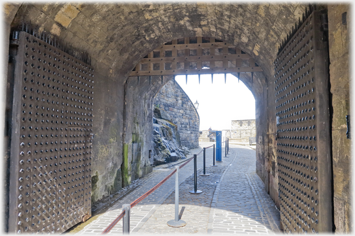 Looking into castle through studded doors and under portcullis.