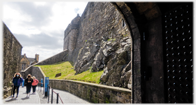 Visitors on path between rocks and wall, seen from doorway.