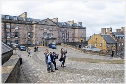 Three visitors in line taking photos, Georgian building behind them.