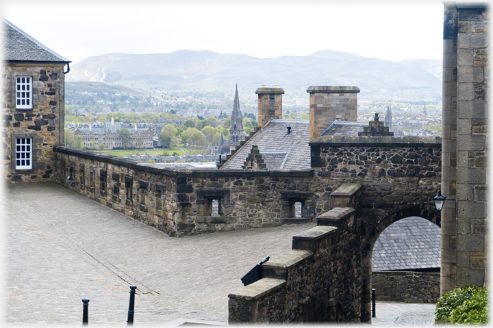 Looking out over a wall across rooftops towards hills.