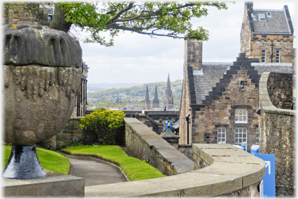 Wall, buildings and urn framing three spires.