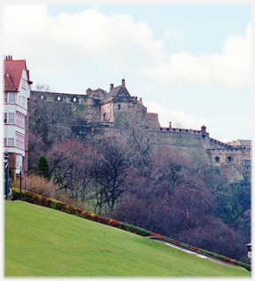 Grass slope with trees and castle beyond.